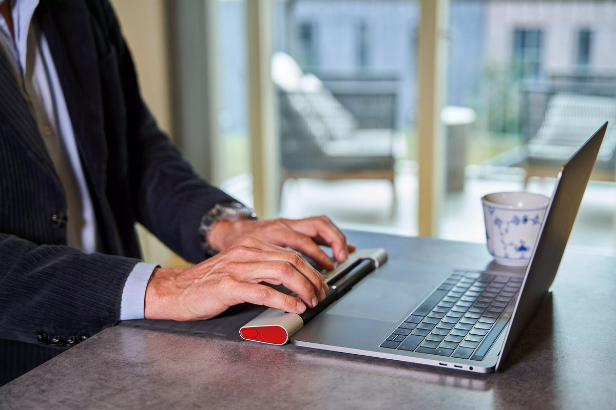Man typing on a laptop with a RollerMouse Red in front of him
