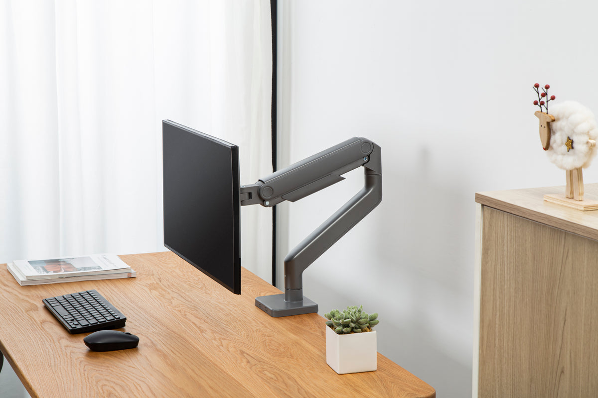 Monitor on a heavy duty arm at a wooden desk in a bright room