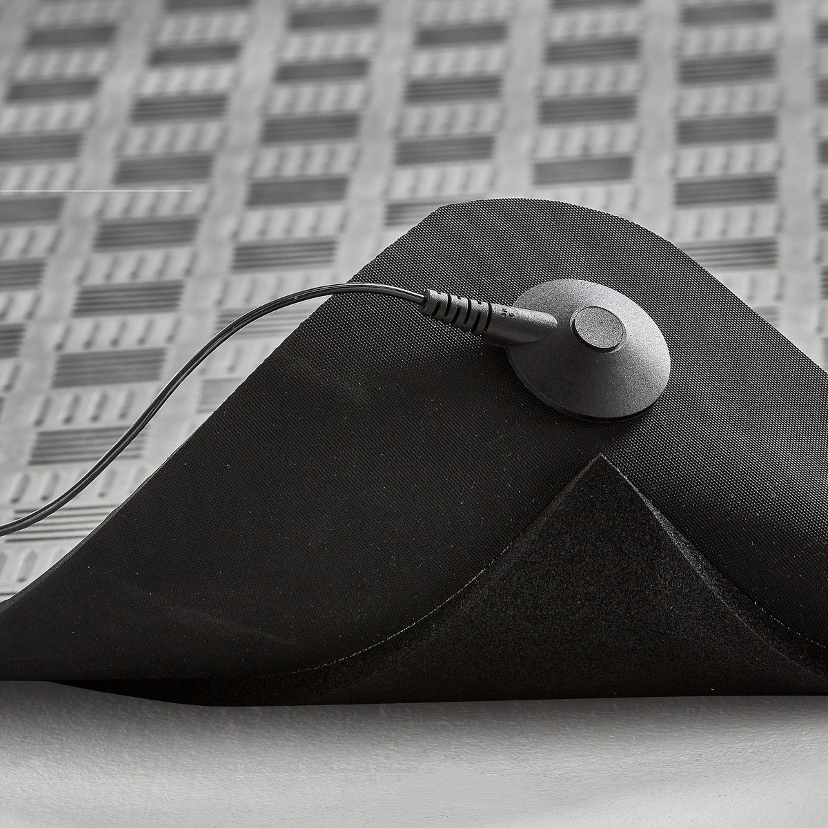 Close-up of the ErgoFinland ESD mat showing the grounding stud and cord