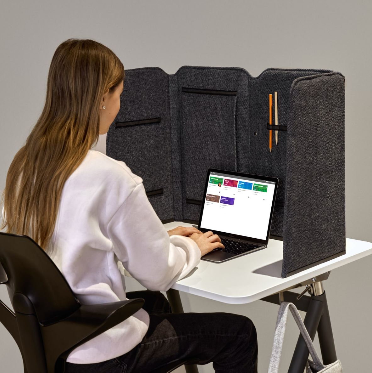 Woman working on a laptop behind a grey Easy School foldable desk screen