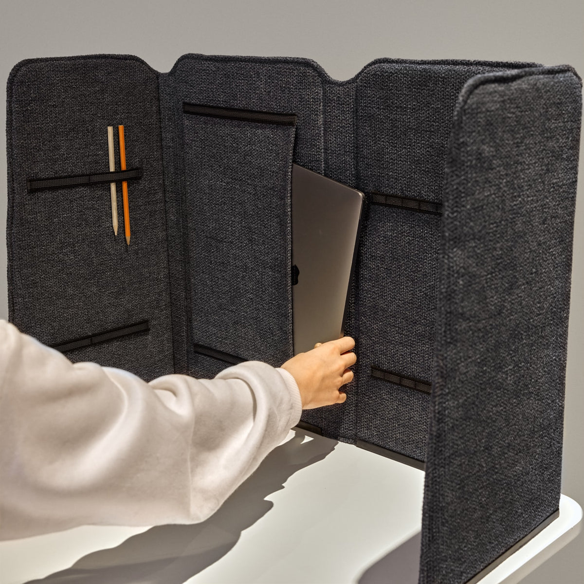 Person unfolding a grey Easy School portable desk screen on a table
