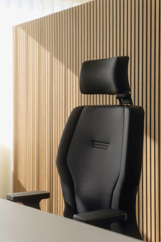 XXLis5 office chair in black in front of a slatted wooden wall