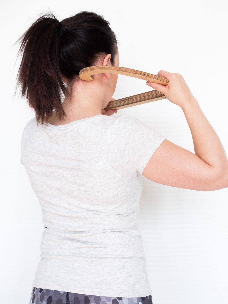 Woman using a HealingHook birch massage hook over her shoulder