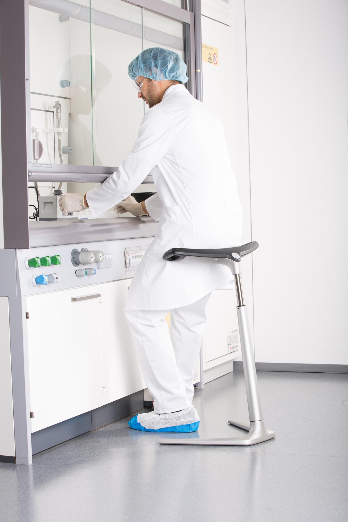 Technician in protective clothing using an ESD protected FIN leaning chair in a laboratory