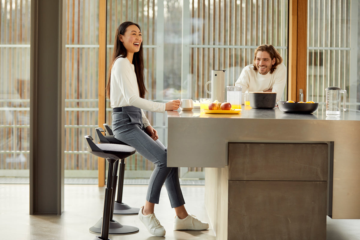 Two people at a kitchen island with a black Muvman active stool
