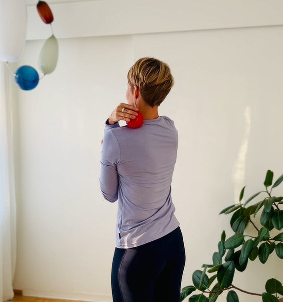 Woman seen from behind using a massage roller on her neck