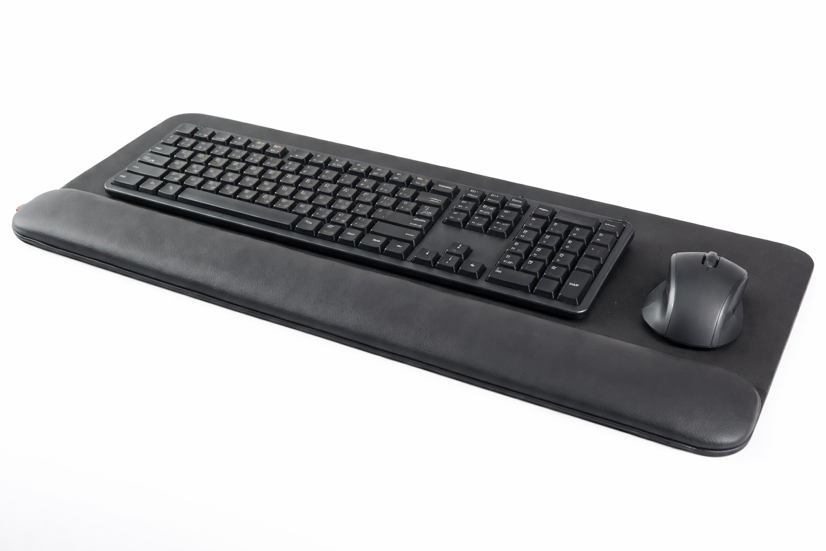 Wide black faux leather wrist rest positioned in front of a keyboard