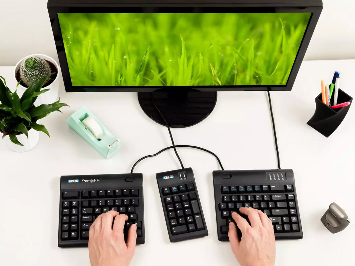 Hands typing on a Freestyle 2 split keyboard at a desk with a monitor