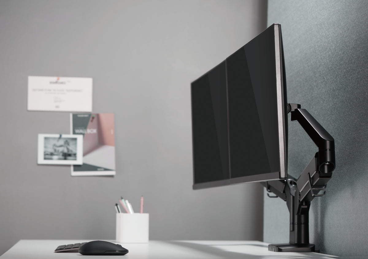 Single monitor mounted on a black gas spring arm above a desk
