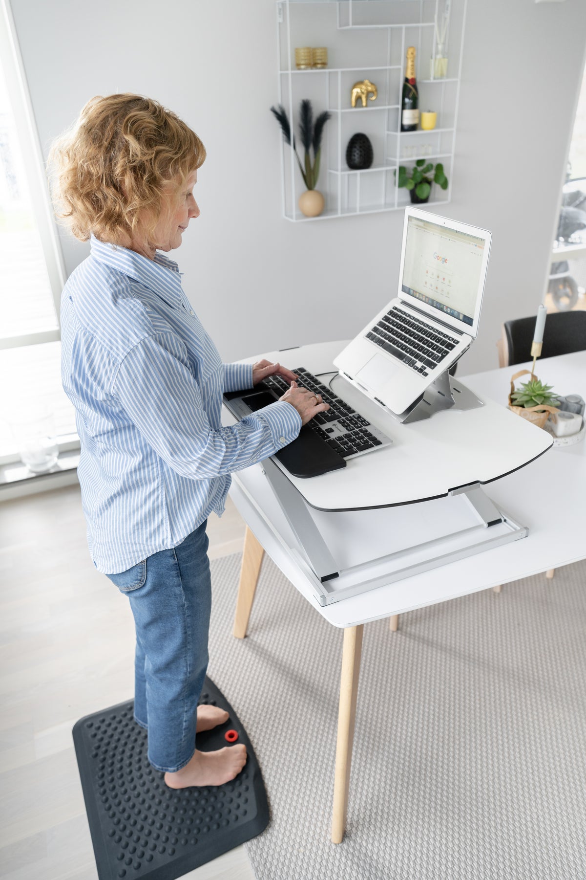 Woman working at a raised GetUpDesk Free tabletop in a bright home office