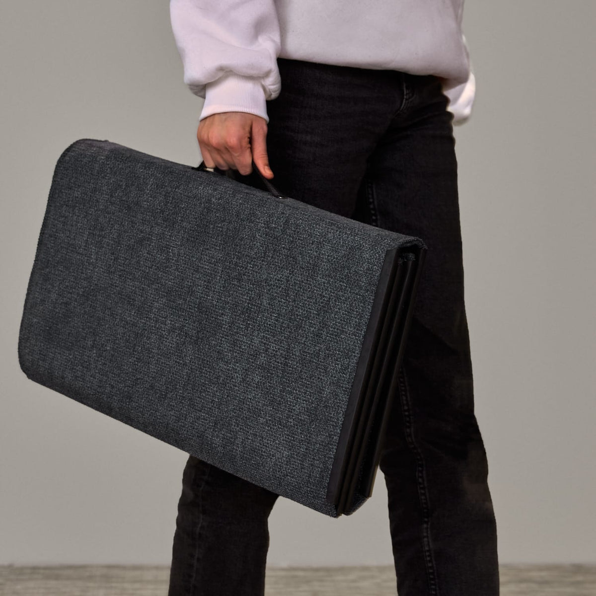 Person carrying a folded Easy School desk screen by its handle like a case