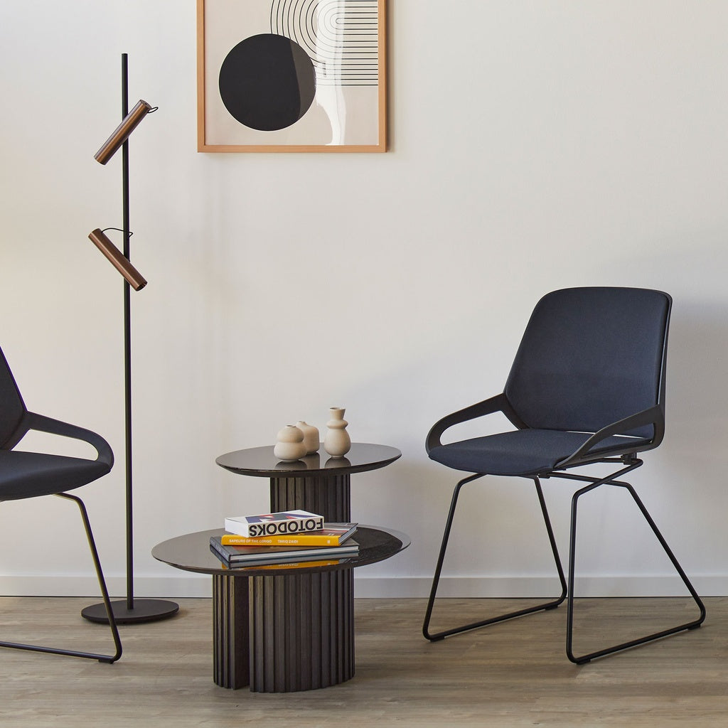 Numo Comfort chair in dark blue Cura fabric beside a side table in a lounge setting