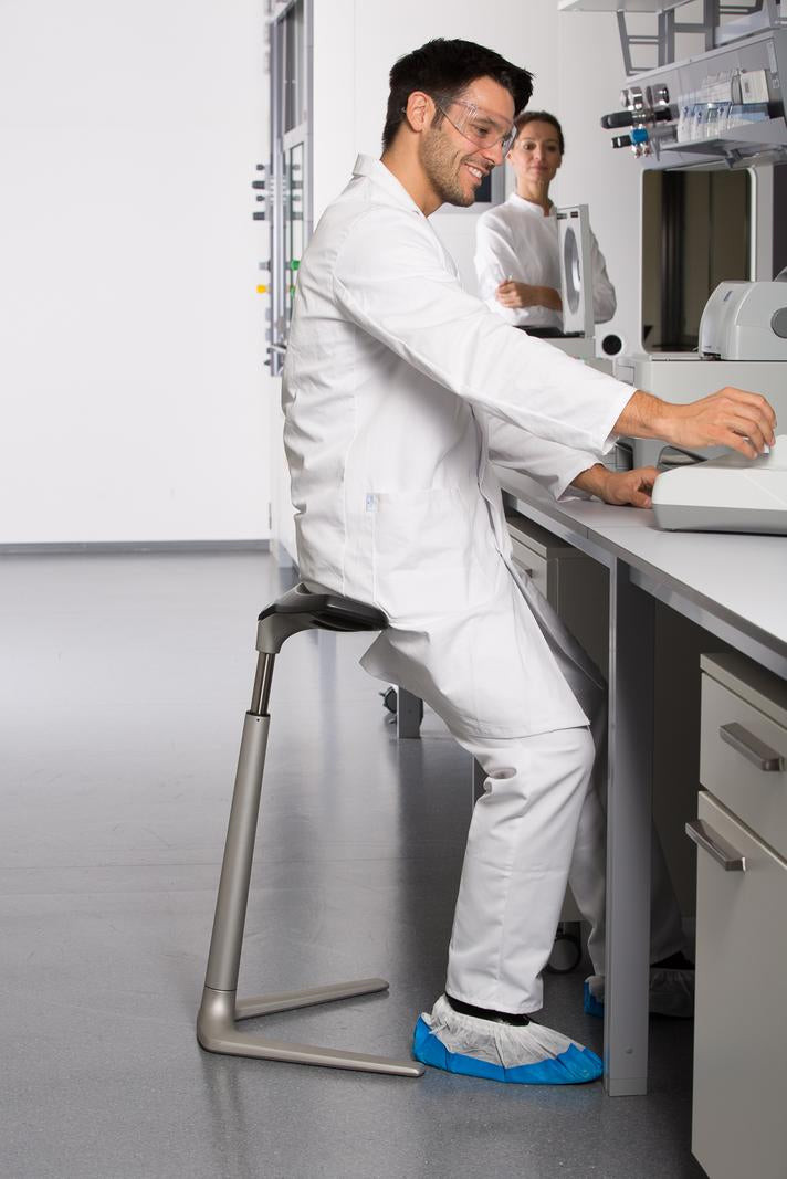 Worker in white overalls leaning on an ESD protected FIN chair at a laboratory bench