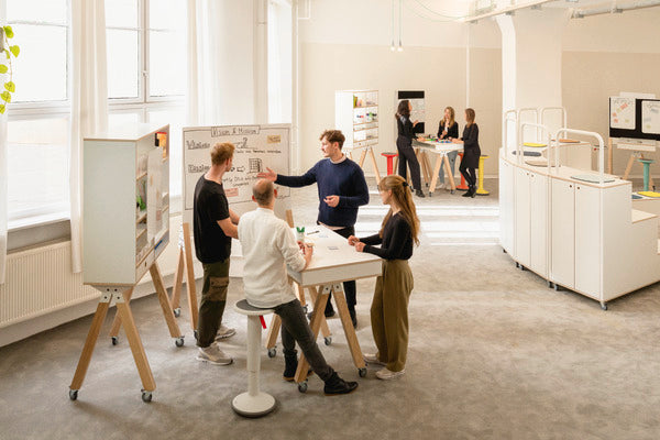 Group of colleagues standing around a TeamDesk standing desk in an office
