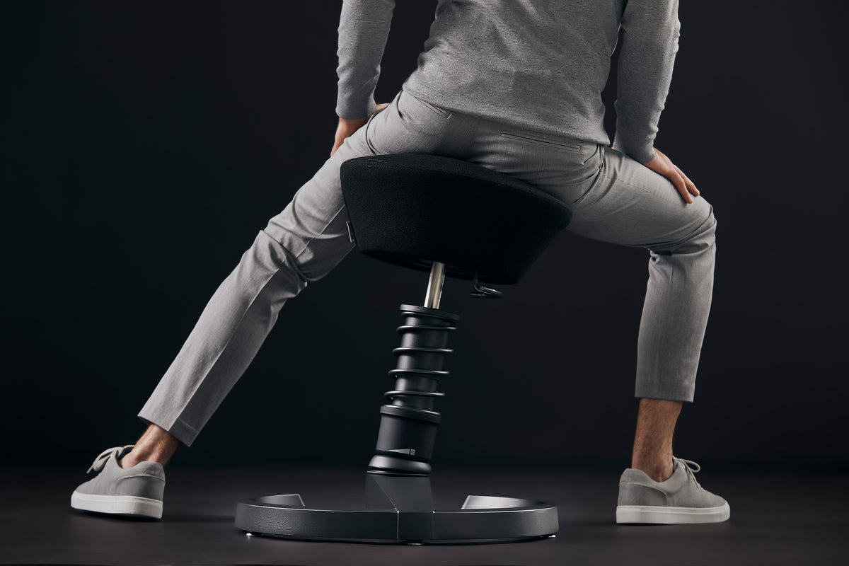 Person leaning forward while perching on a black Swopper active chair