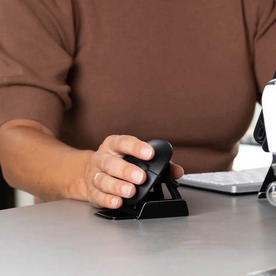 Close-up of a hand operating an R-Go Twister ergonomic mouse on a desk