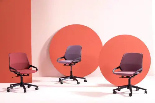 Three Numo Task active chairs in different colours against a red backdrop