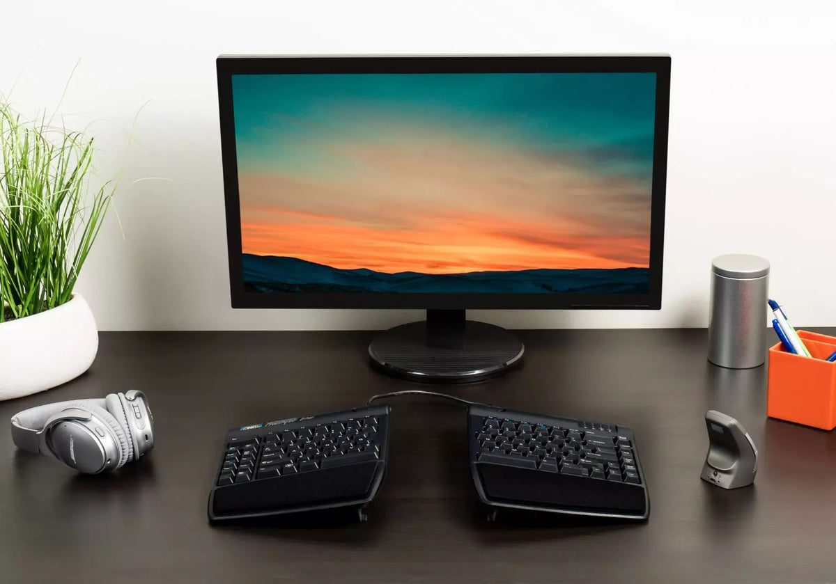 Desk with a monitor and a Freestyle 2 keyboard raised on tenting brackets