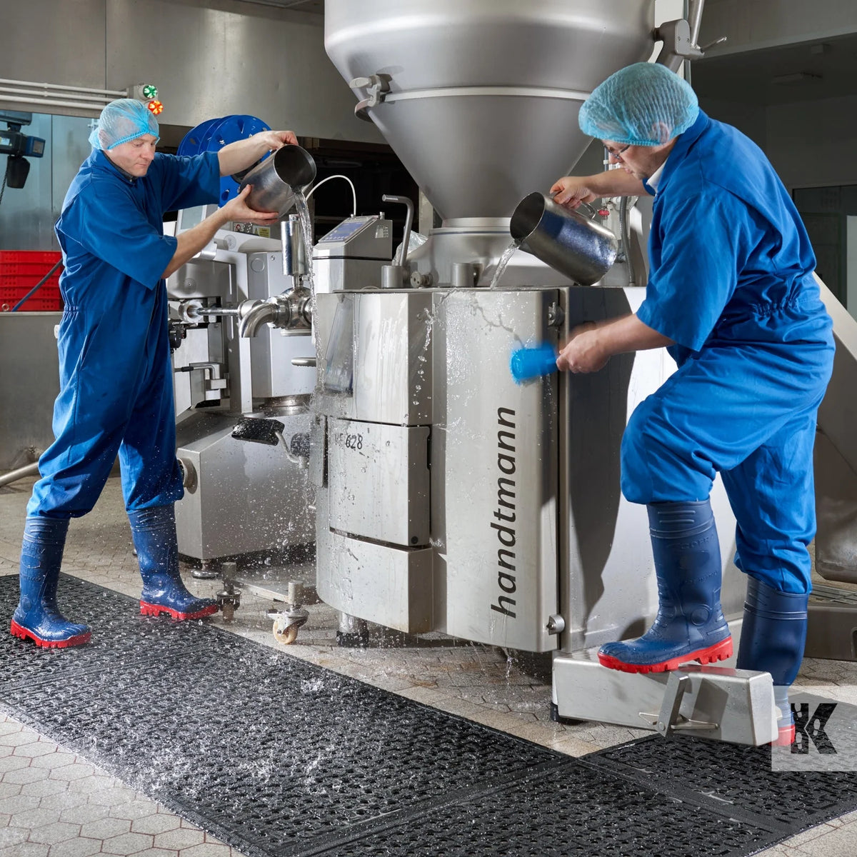 Workers in protective clothing standing on nitrile mats in a food production plant
