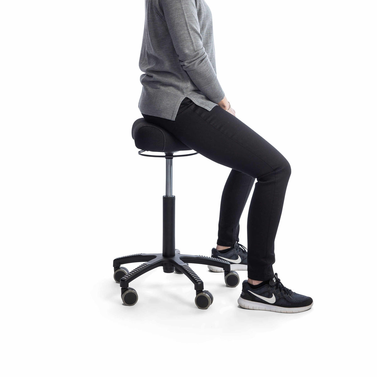 Person sitting on a black ergonomic chair with wheels, demonstrating comfort and posture support.
