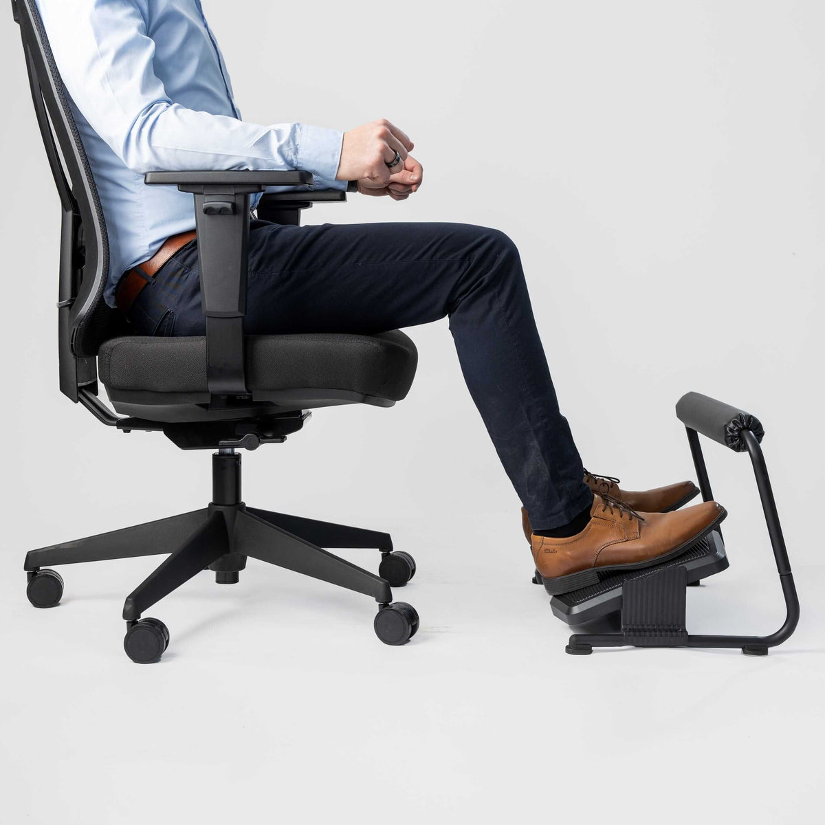 Man seated in an office chair with his feet on a Foot support Flex