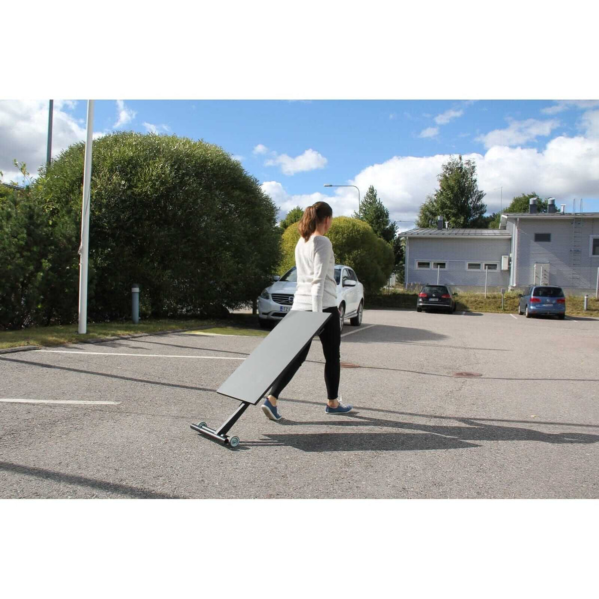 Woman carrying a folded GetUpDesk Move desk outdoors