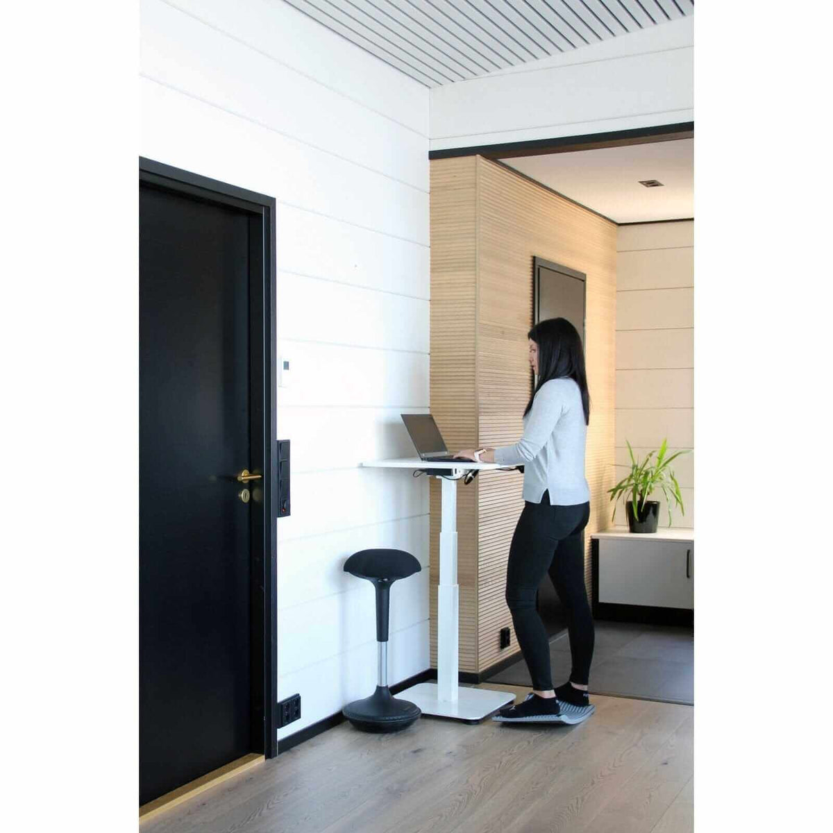 Woman working at a black GetUpDesk single electric standing desk in an office