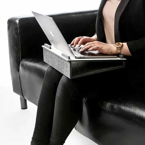 Woman using a laptop on a Lapsteri stand on her lap in an armchair